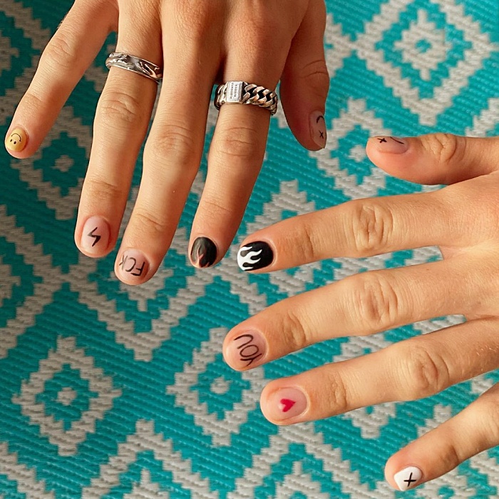 Hombre joven con manicura masculina, estilo moderno en negro, blanco, rojo, amarillo, azul y gris
