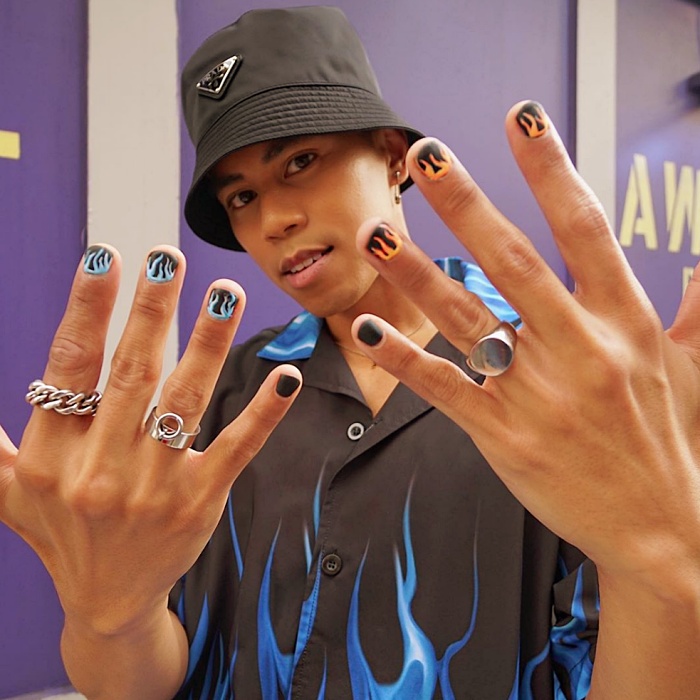 Hombre joven con manicura masculina, estilo moderno en negro, blanco, rojo, amarillo, azul y gris