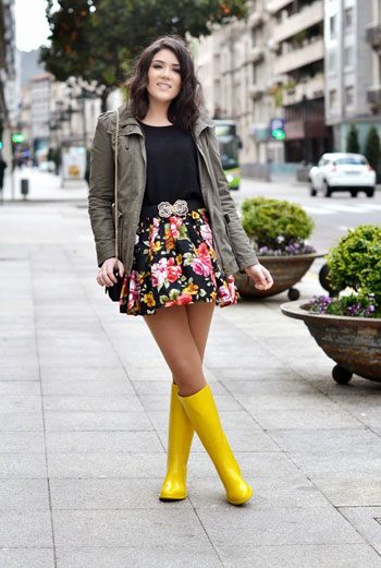 Chica usando un outfit de lluvia con botas, paraguas y chaqueta
