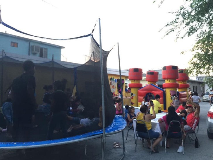 Personas en una fiesta infantil con inflables y mesas
