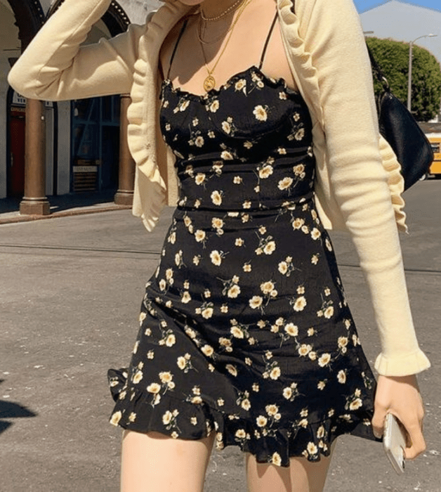 chica con vestido negro de flores amarillas, tirantes cortos con vuelos, cárdigan amarillo pastel de manga larga