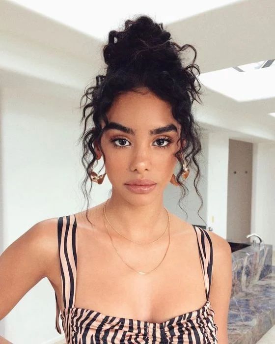 Chica con cabello rizado y bun alto ;13 Peinados para enchularte en menos de 15 minutos
