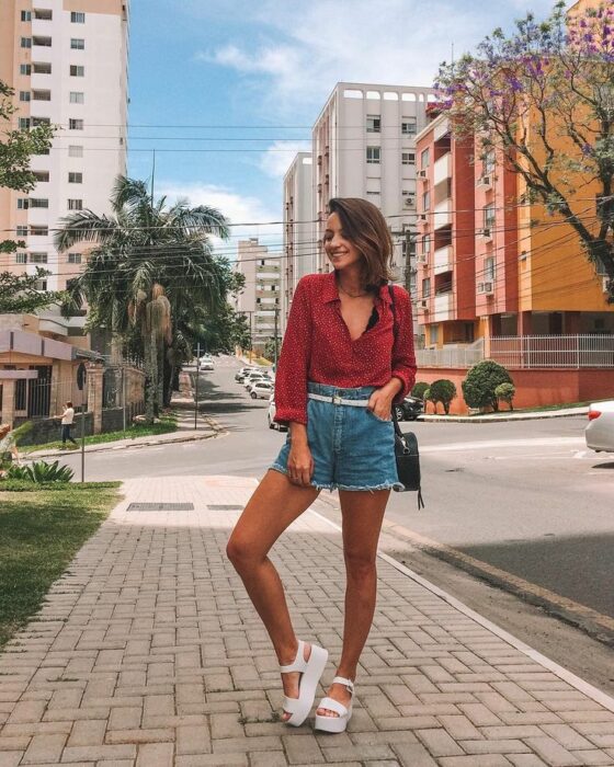 Chica con shorts de mezclilla, blusa roja y sandalias de plataforma