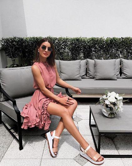 Chica sentada luciendo un vestido rosa con sandalias de plataforma