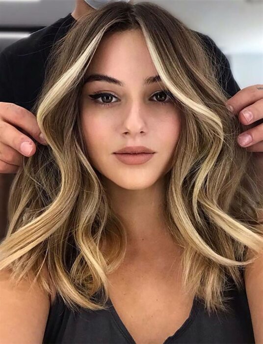Chica con el cabello teñido en rubio con reflejos en tono caramelo