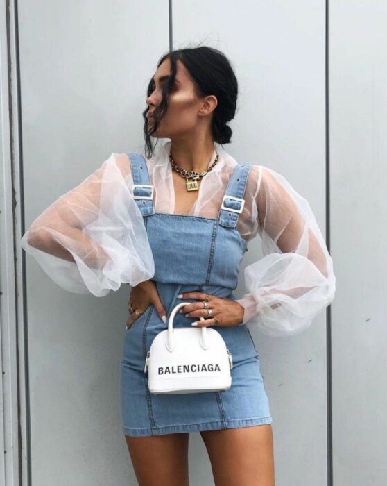 Chica posando para una fotografía mientras usa un bolso pequeñito