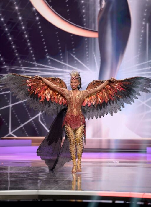 Miss universo usando su traje típico en forma de águila en colores rojo con negro