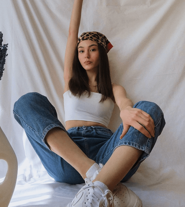 chica de cabello largo usando un crop top blanco, negro, beige, café, verde, azul de manga larga, corta, con jeans ajustados, pantalones negros de cuero, bolso pequeño de mano