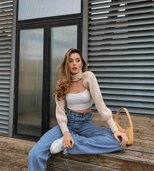 chica de cabello largo usando un crop top blanco, negro, beige, café, verde, azul de manga larga, corta, con jeans ajustados, pantalones negros de cuero, bolso pequeño de mano