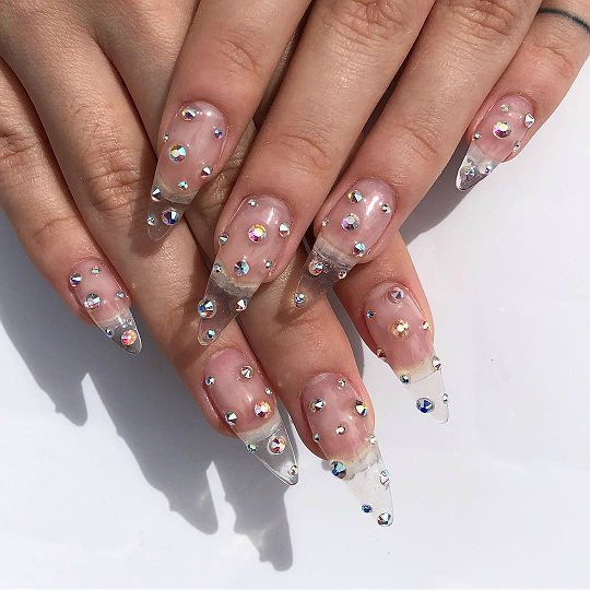 Diseño de uñas transparentes decoradas con estoperoles