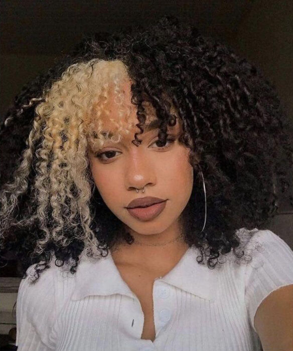 Chica con el cabello rizado y teñido de color negro con el copete rubio