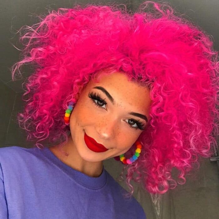 Chica con el cabello rizado y teñido de color rosa fucsia