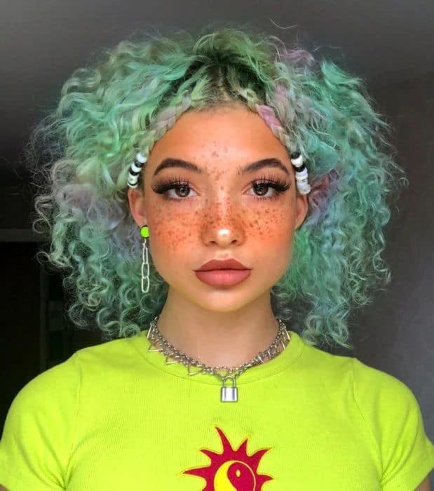Chica con el cabello rizado y teñido de color verde con morado