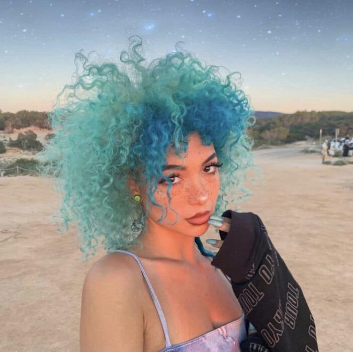 Chica con el cabello rizado y teñido de color azul