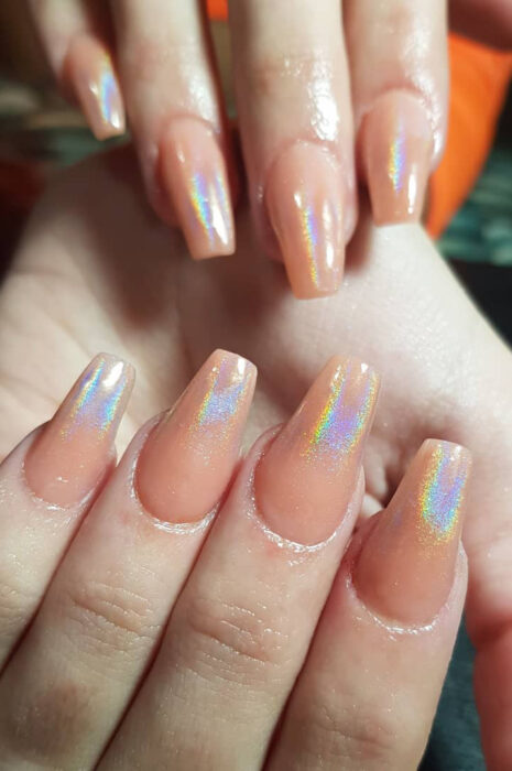 Chica con uñas holográficas en tonos nude con plateado