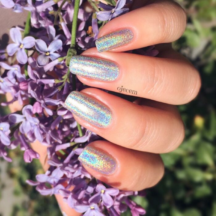Chica con uñas holográficas en tonos plateados