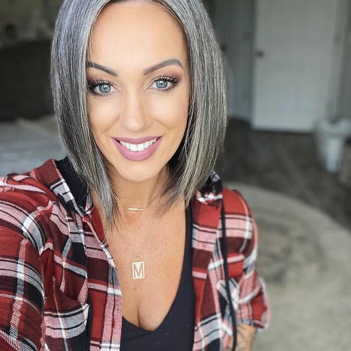 Miranda, mujer que dejó de teñir sus canas posando para una foto mientras está en su recamara 