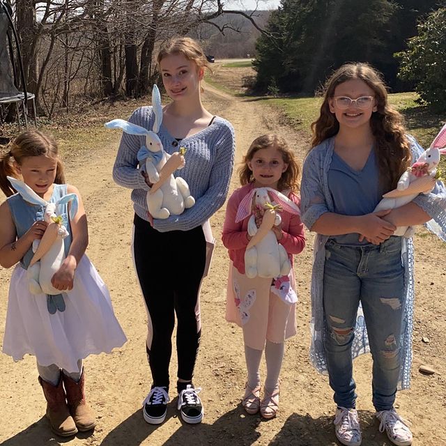 Niñas en un terreno cargando conejos de pascua con dulces 