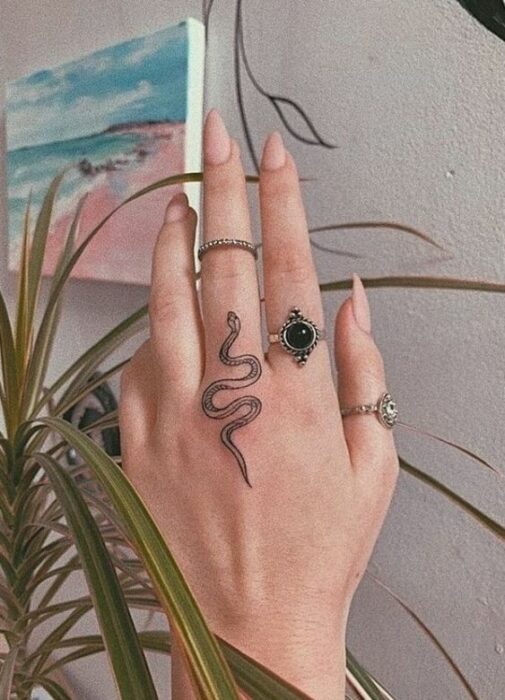 Chica llevando tatuaje de serpiente en el dedo; Tatuajes ocultos que desearás llevar