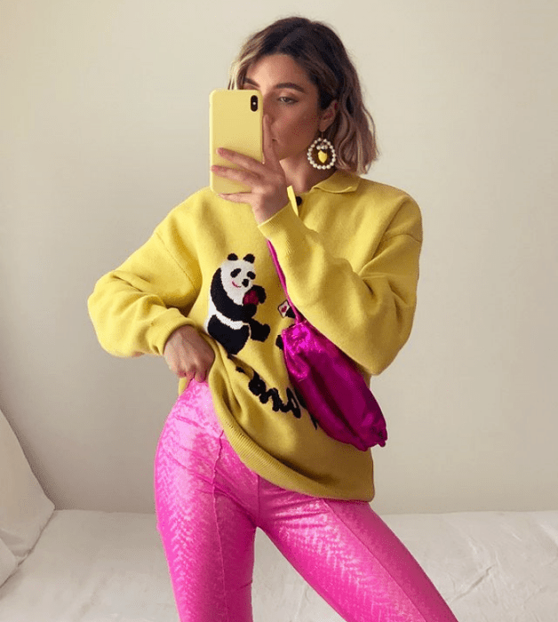 joven de cabello claro con sudadera amarilla con panda, leggings rosas neón y bolso fucsia