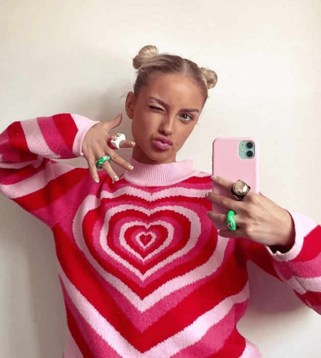 joven rubia con suéter rojo y rosa de corazones y anillos de colores brillantes