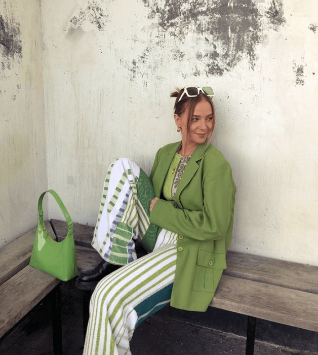 joven de cabello oscuro con gafas verdes, blazer holgado verde y top verde limón