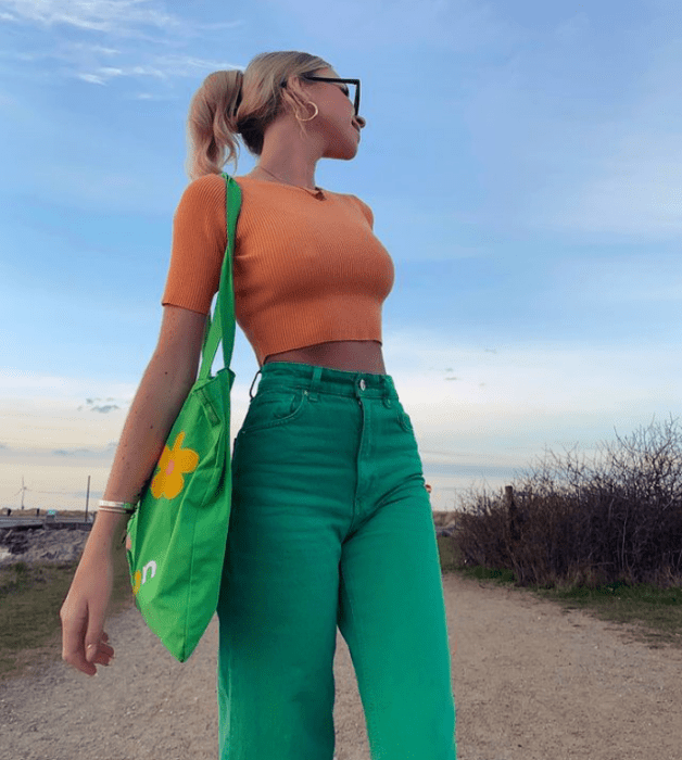 joven rubia con crop top naranja pastel y pantalones verde brillante