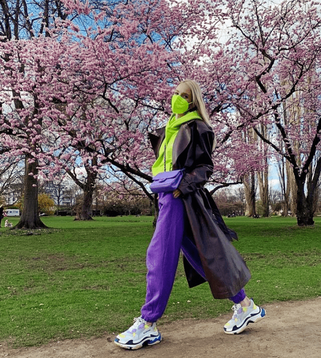 joven rubia con bufanda verde limón, pants morados y abrigo oscuro