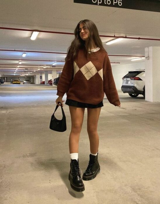 chica con outfit colegial y suéter amplio y botas militares; 13 Outfits colegiales que extrañas de la escuela