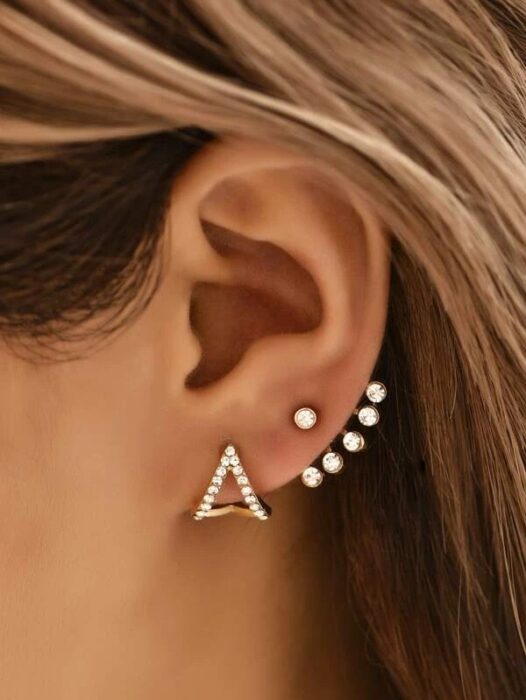 Chica usando unos aretes en forma de triángulo con detalles 