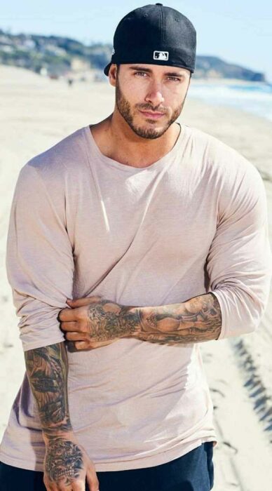 Hombre tatuado vistiendo una camiseta 3/4 que muestra sus tatuajes