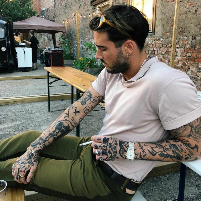 Chico sentado en una banca fumando un cigarrillo