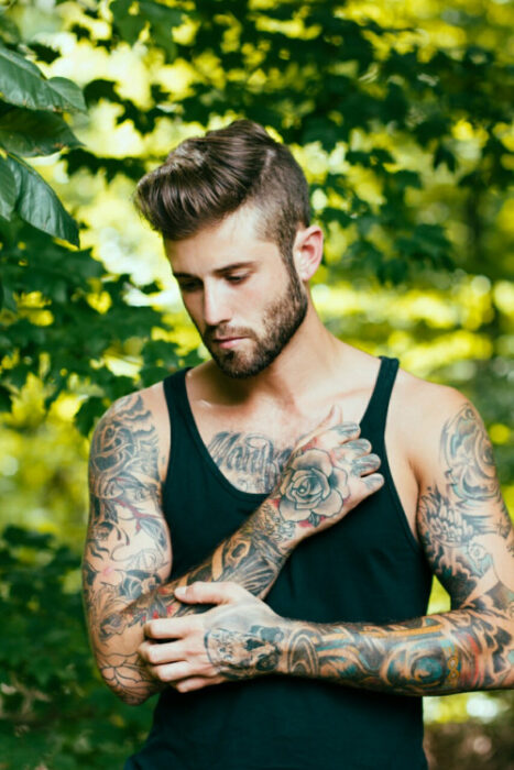 Chico con tatuajes reflexionando en un jardín