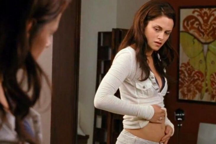 Mujer viendo su panza en el espejo mientras se toma una selfie