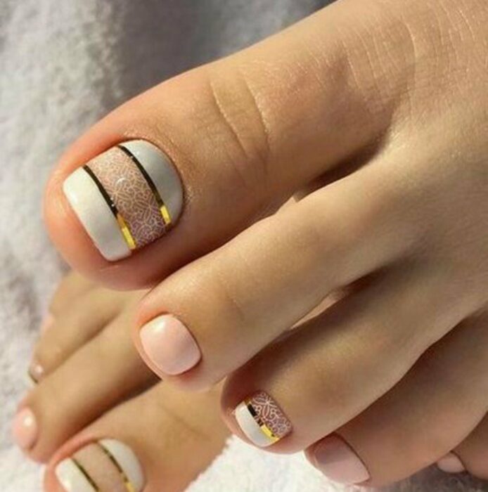 Diseño de uñas para pies en color blanco con líneas doradas y blancas