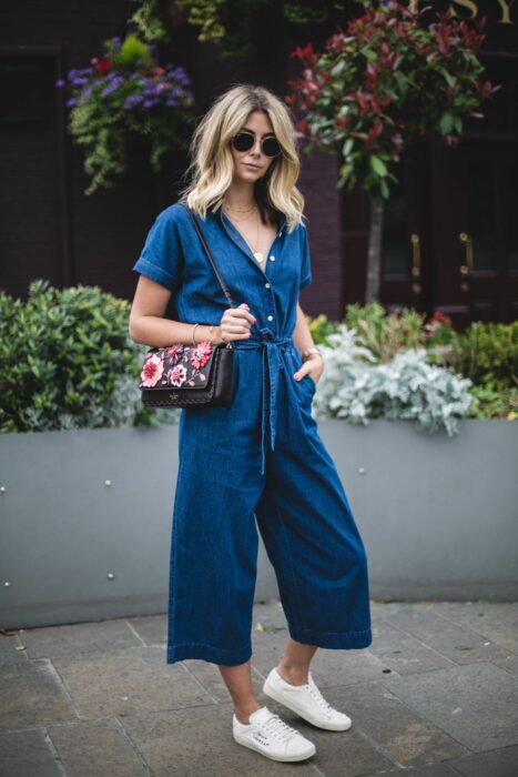 Chica usando un jumpsuit de color mezclilla con tenis blancos