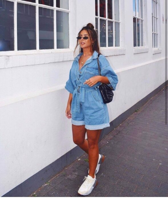 Chica usando un jumpsuit de color mezclilla con tenis blancos