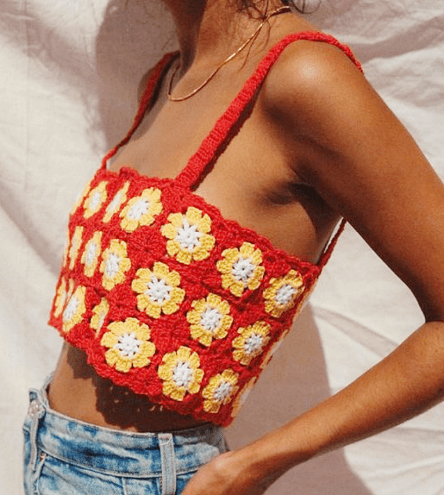 chica morena con top de tirantes rojo brillante, flores amarillas y jeans ajustados