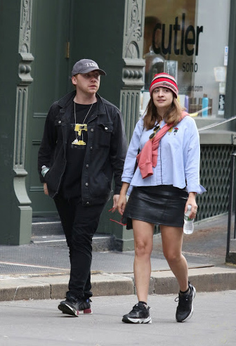 Georgia Groome y Rupert Grint caminando mientras van tomados de la mano