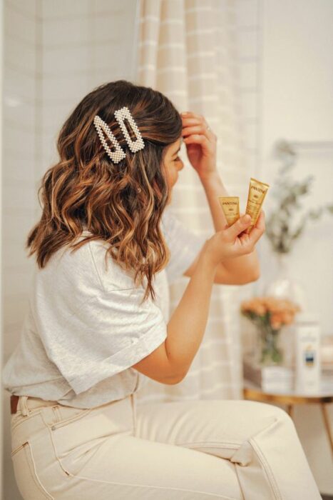Chica con el cabello hasta los hombros sujetados con pinzas decoradas con perlas