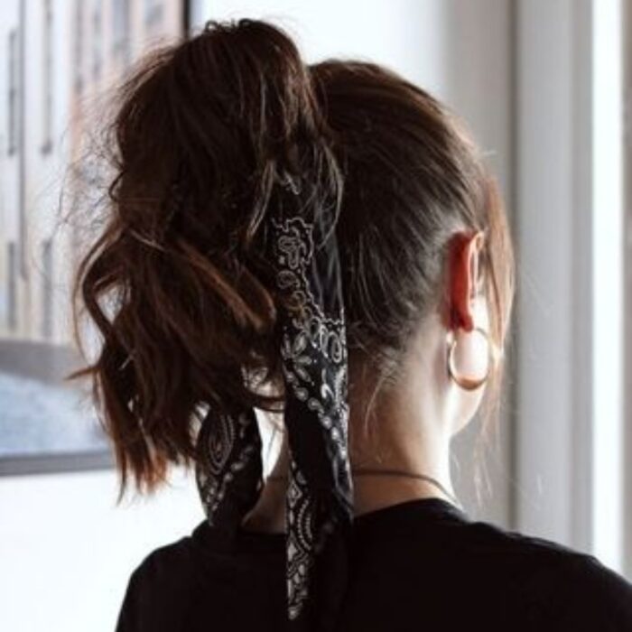 Chica con el cabello hasta los hombros sujetado con una pañoleta negra