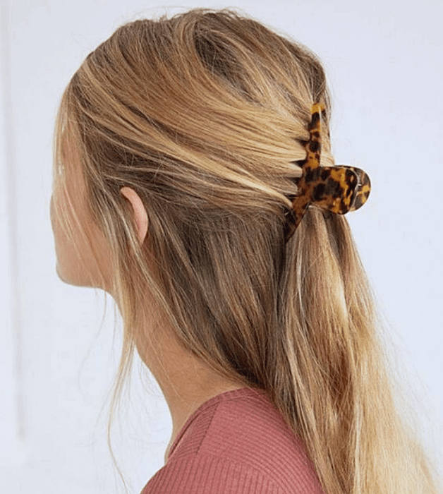 chica de cabello rubio usando una pinza de tortoise café con amarillo, ámbar, top rosa