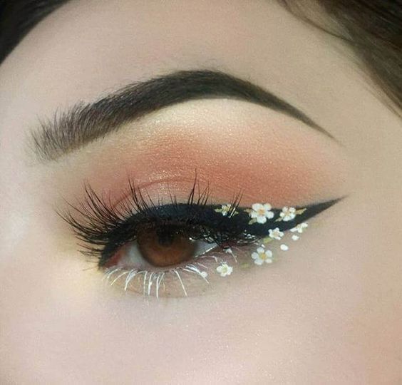 Chica con delineado negro decorado al final con flores blancas; Delineados con flores para una mirada llena de color