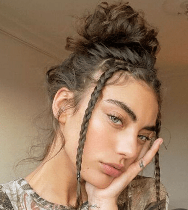 mujer de cabello rizado oscuro con un chongo y trencitas en los lados