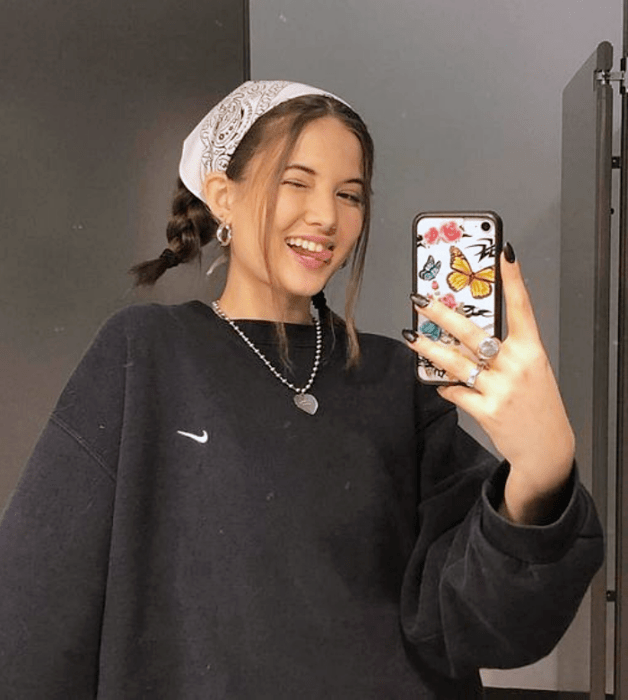 mujer de cabello castaño con trenzas, pañoleta de flores y sudadera negra