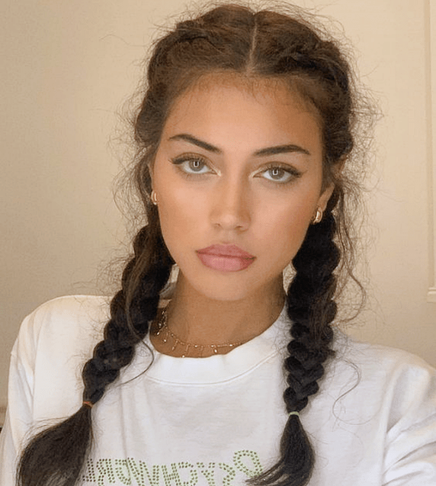 mujer de cabello oscuro con largas trenzas a los lados, usando una camiseta blanca