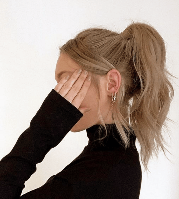 mujer rubia con un chongo alto, top negro de cuello alto y mangas largas