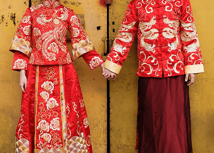 pareja de novios chinos agarrados de la mano con vestimenta típica de la cultura china