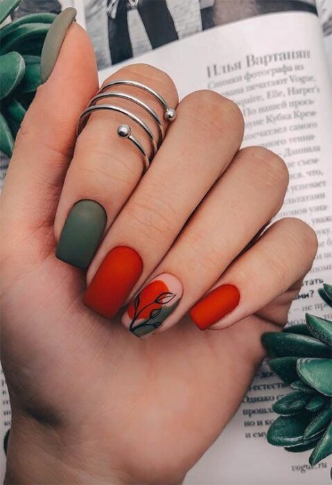Manicura en tonos rojo y verde, decorado con una hoja en tono negro; Uñas bonitas con diseño de hojitas