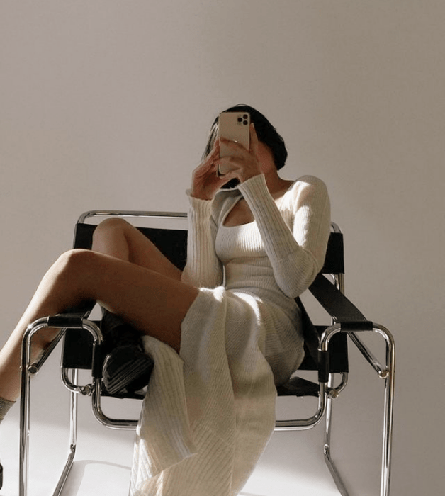 chica de cabello corto castaño con vestido beige ajustado de manga larga y botas de cuero largas